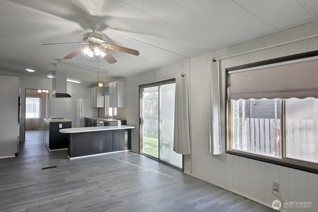 a living room with stainless steel appliances kitchen island hardwood floor and a large window
