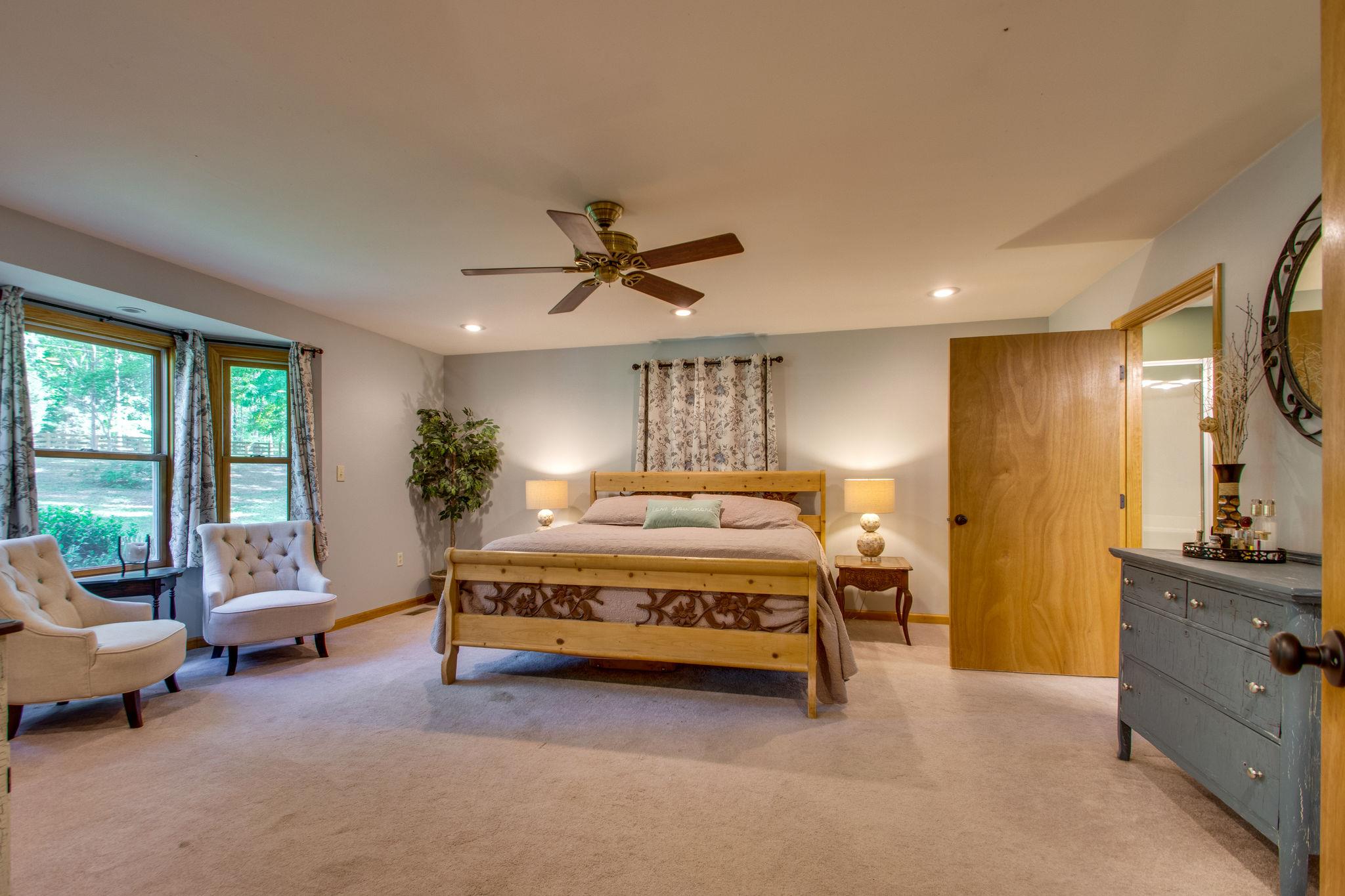 1017 Deer Ridge Road Kingston Springs, TN 37082 - Photo 14 of 29 a spacious bedroom with a bed a couch and a large window