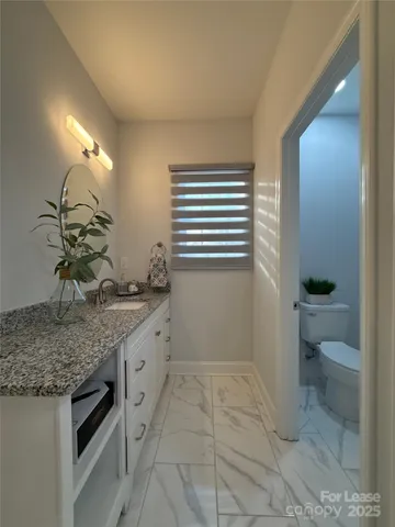 a bathroom with a granite countertop sink a toilet and a mirror