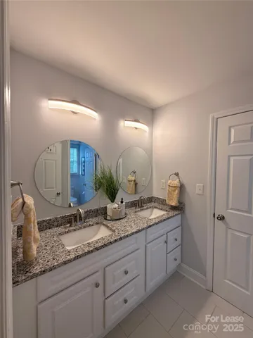 a bathroom with a granite countertop double vanity sink and mirror