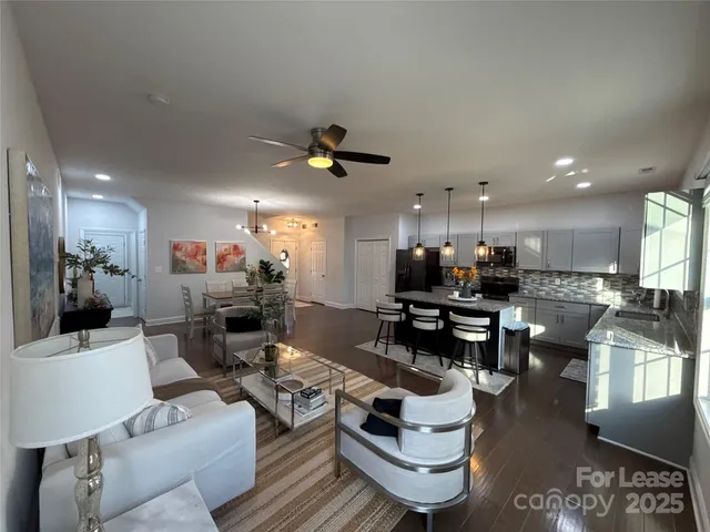 a living room with couches kitchen view and a dining table with kitchen view