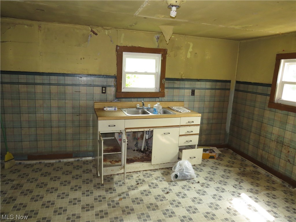 1054 Bergholz Road Southeast Bergholz, OH 43908 - Photo 5 of 11 Kitchen with sink, tile walls, and backsplash