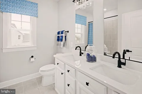 a bathroom with double vanity a toilet a and a window