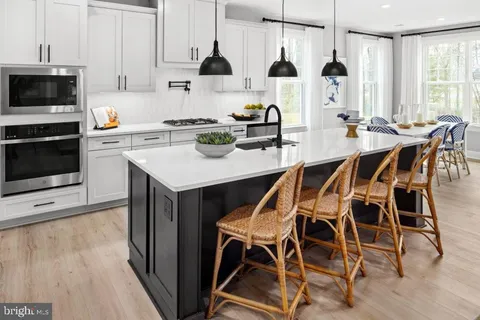 a kitchen with stainless steel appliances kitchen island granite countertop a table chairs microwave and sink