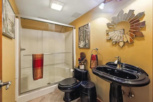 a view of barn with a small yard plants and large trees