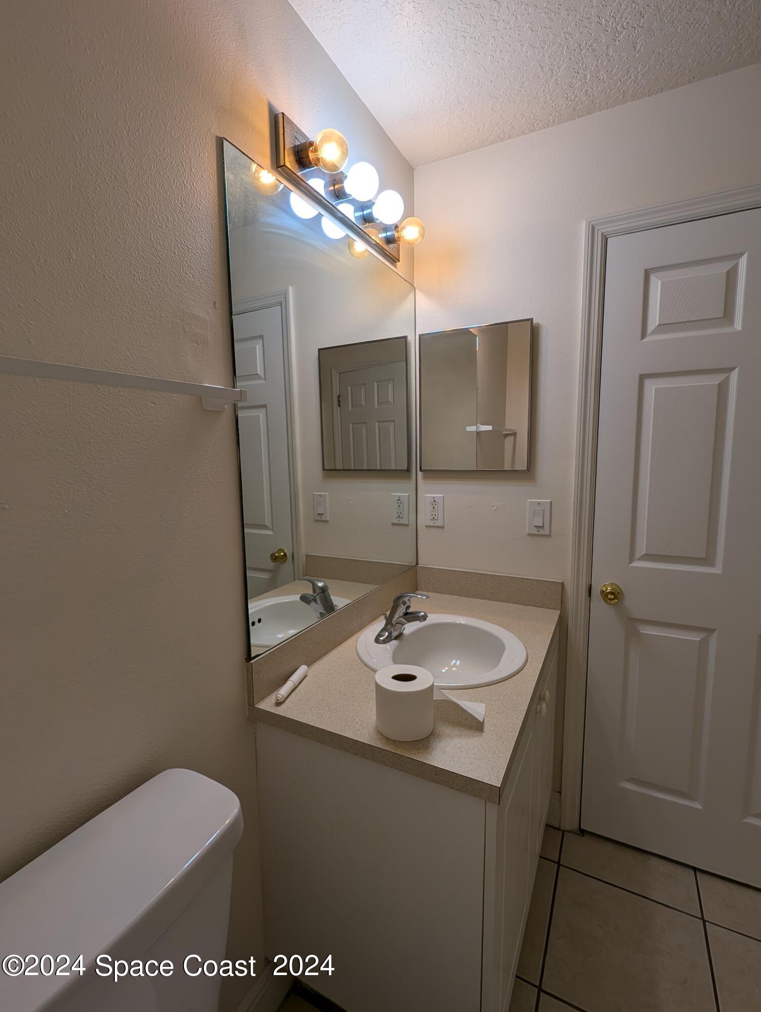745 Luminary Circle, Unit 101 Melbourne, FL 32901 - Photo 15 of 32 a bathroom with a toilet sink and mirror