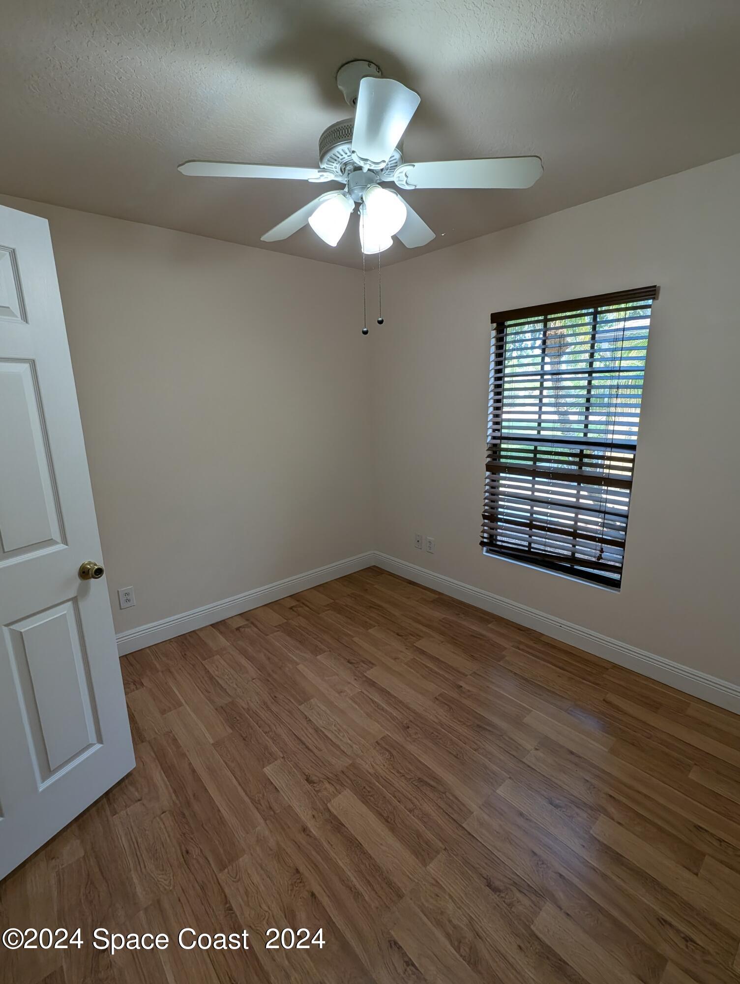 745 Luminary Circle, Unit 101 Melbourne, FL 32901 - Photo 18 of 32 an empty room with wooden floor fan and windows