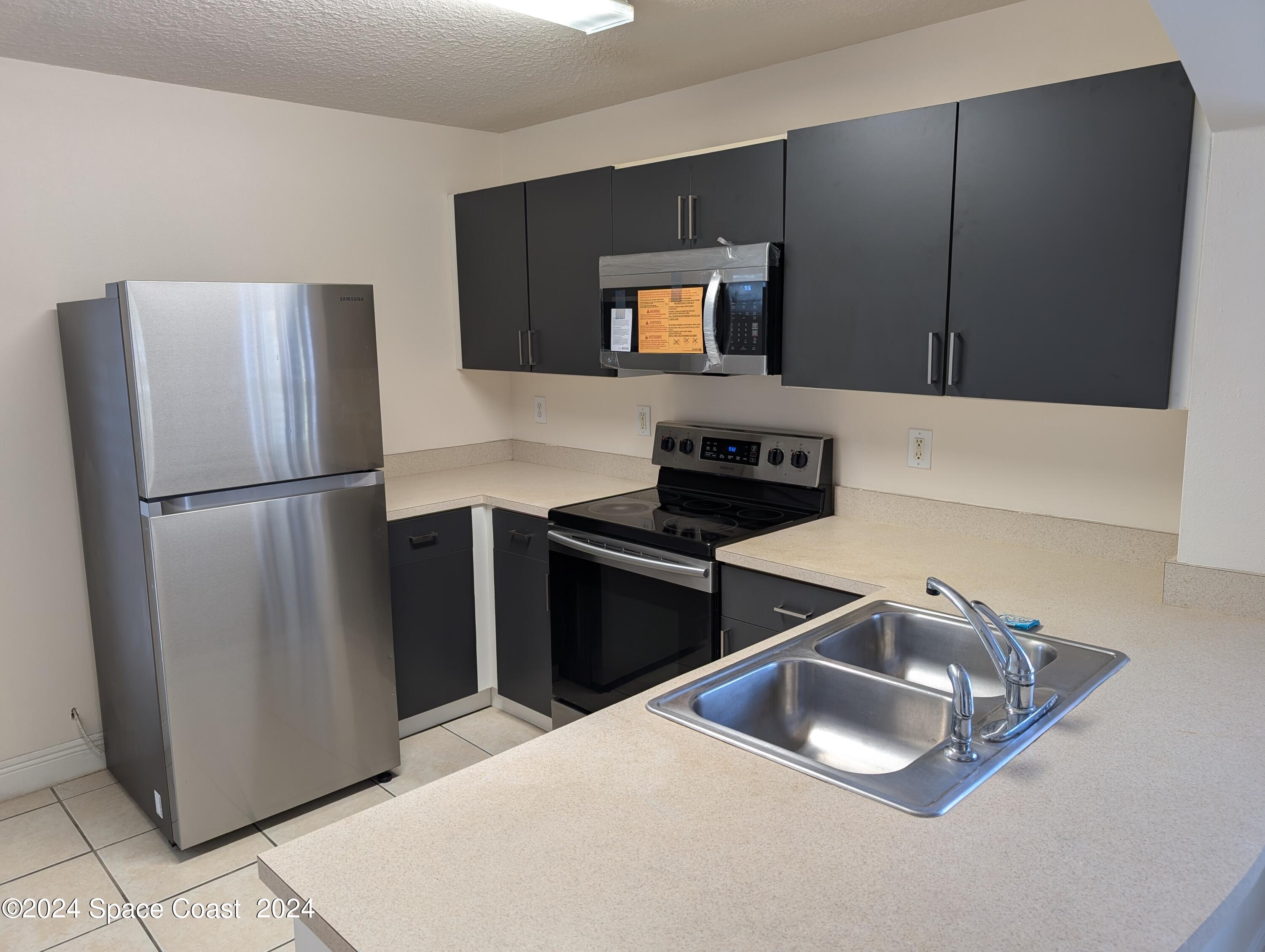 745 Luminary Circle, Unit 101 Melbourne, FL 32901 - Photo 3 of 32 a kitchen with a refrigerator sink and microwave