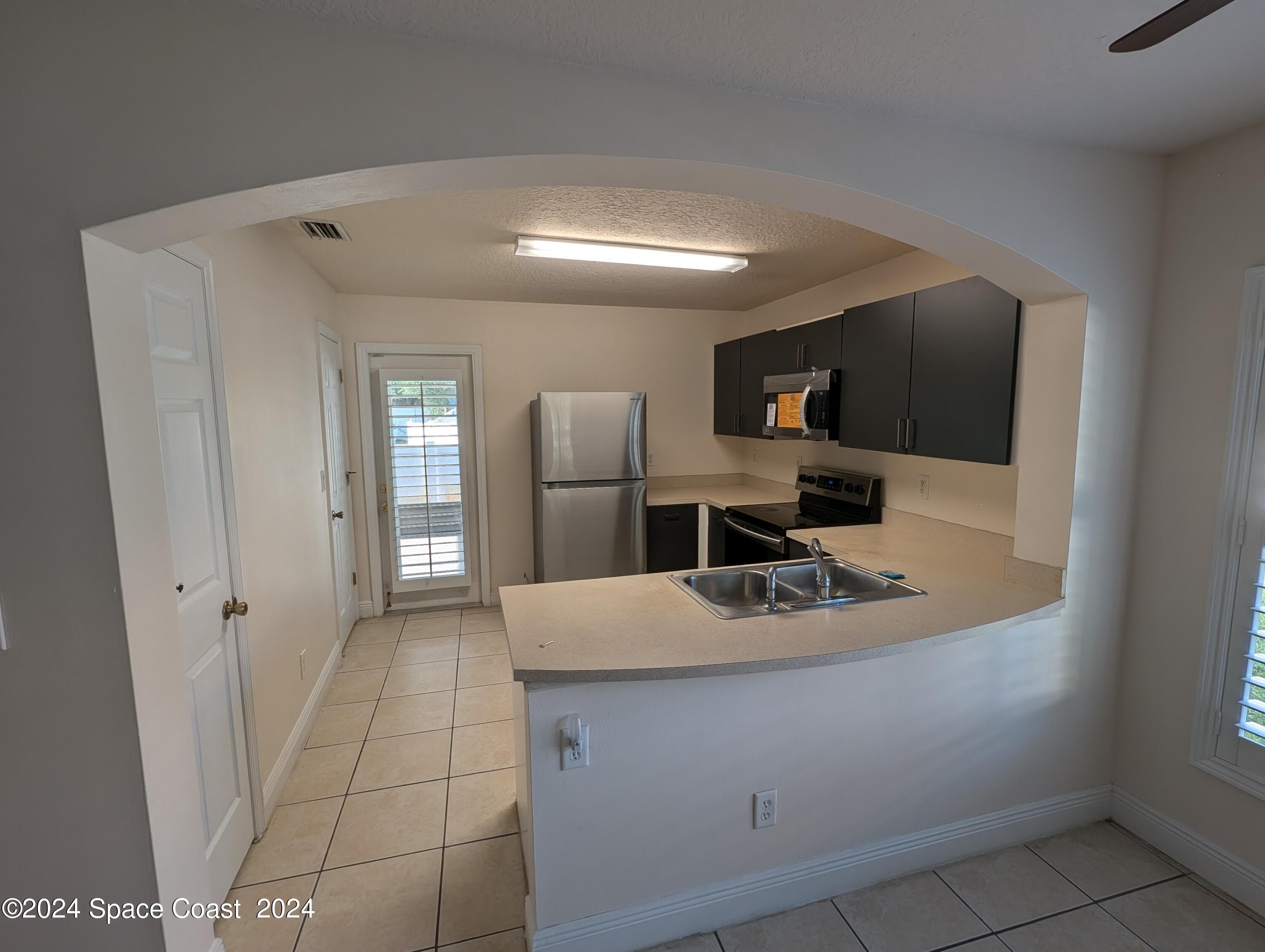 745 Luminary Circle, Unit 101 Melbourne, FL 32901 - Photo 9 of 32 a kitchen with stainless steel appliances granite countertop a sink and a refrigerator