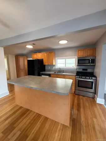 a large kitchen with stainless steel appliances a large counter top a stove and a wooden floors