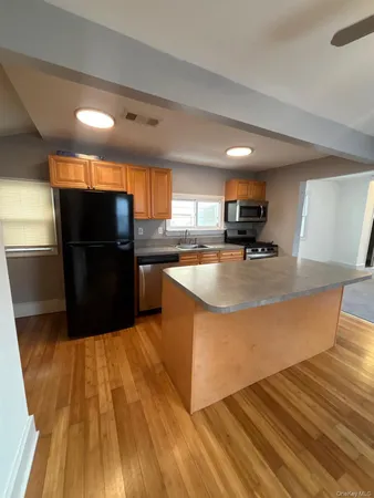 a kitchen with stainless steel appliances wooden floors stove and cabinets