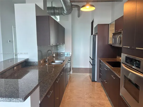 a kitchen with stainless steel appliances granite countertop a sink a stove and a refrigerator