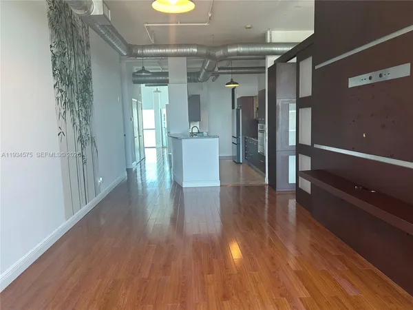a hallway with wooden floor chandelier and windows