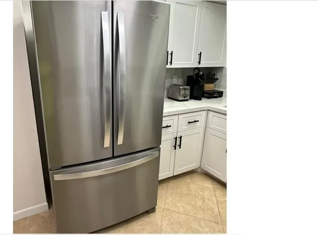 a kitchen with white cabinets and refrigerator