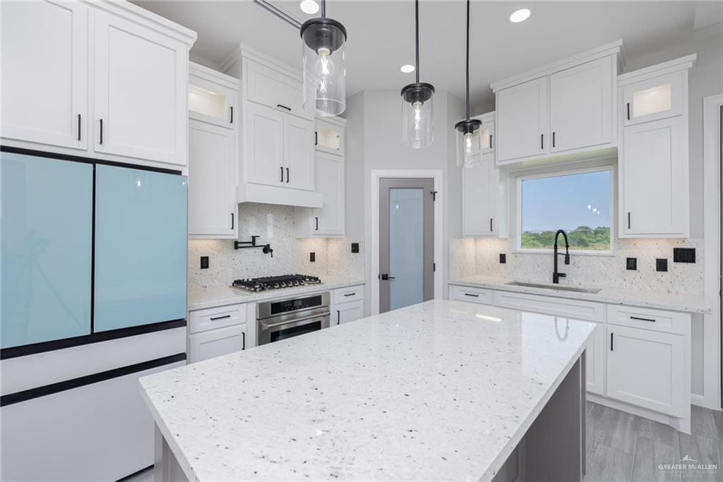 7710 Navel Lane Mission, TX 78574 - Photo 7 of 20 a large kitchen with stainless steel appliances a stove a sink a refrigerator and white cabinets with wooden floor