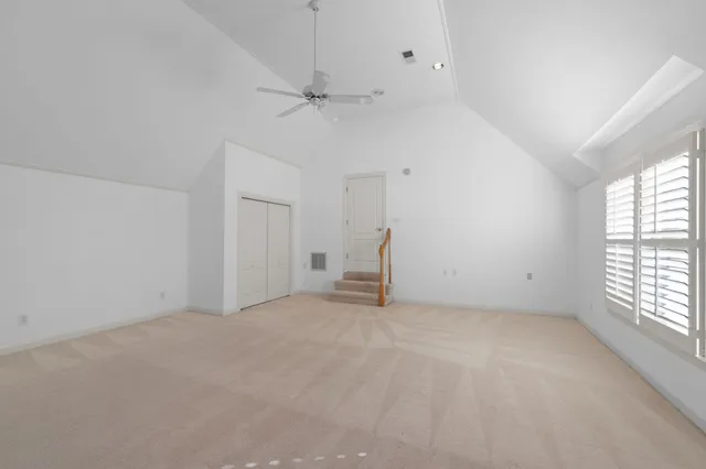 an empty room with chandelier fan and windows