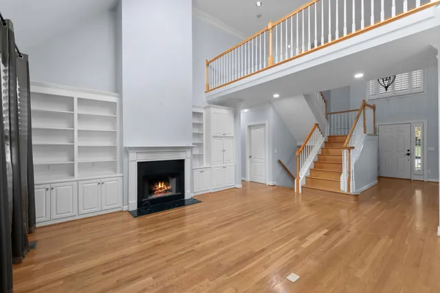 a view of an empty room with wooden floor fireplace and stairs