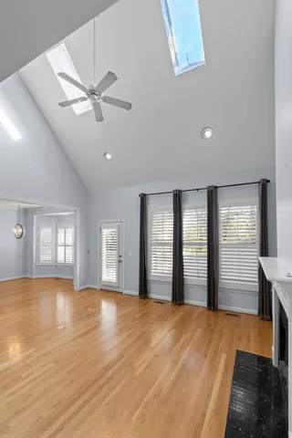 a view of an empty room with window and wooden floor