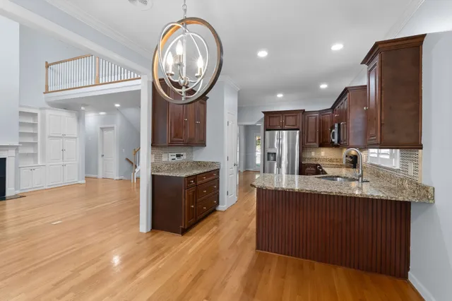 a kitchen with stainless steel appliances granite countertop a sink a stove top oven and wooden floors