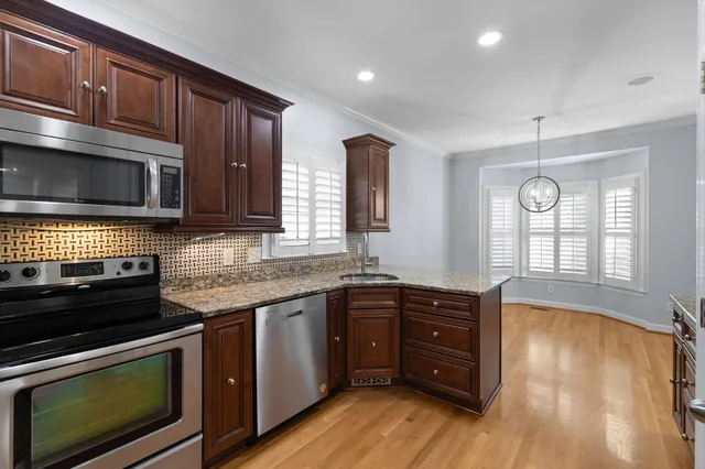a kitchen with stainless steel appliances granite countertop wooden cabinets and a stove top oven