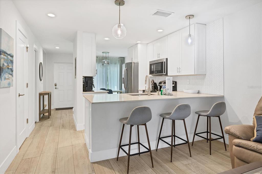 1762 Stickney Point Road, Unit 204 Sarasota, FL 34231 - Photo 11 of 38 a kitchen with stainless steel appliances granite countertop a table chairs sink refrigerator and microwave