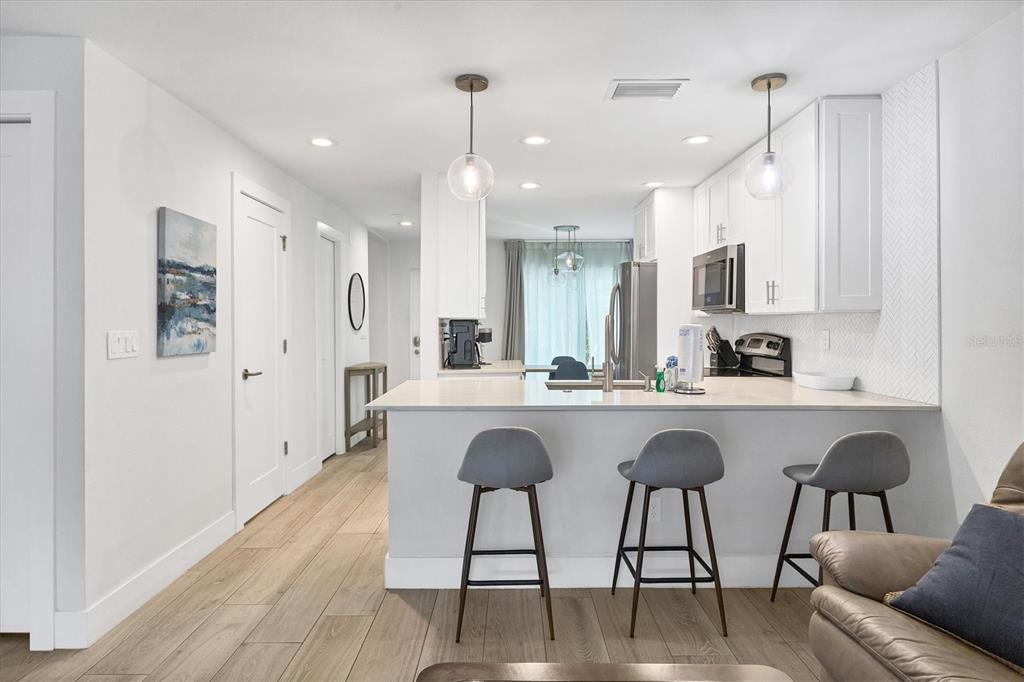 1762 Stickney Point Road, Unit 204 Sarasota, FL 34231 - Photo 10 of 38 a kitchen with stainless steel appliances granite countertop a refrigerator a sink dishwasher a dining table and chairs with wooden floor