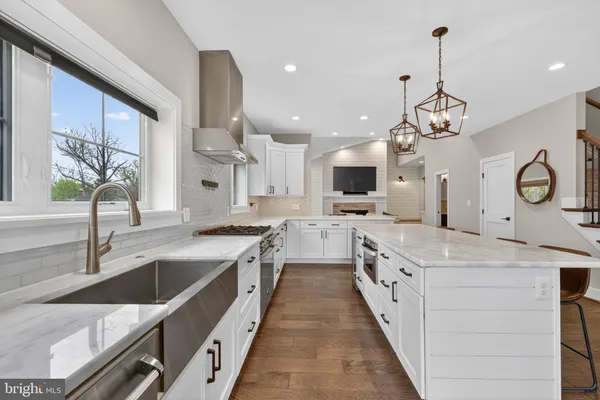 a large kitchen with stainless steel appliances granite countertop a sink dishwasher a stove and a dining table with wooden floor