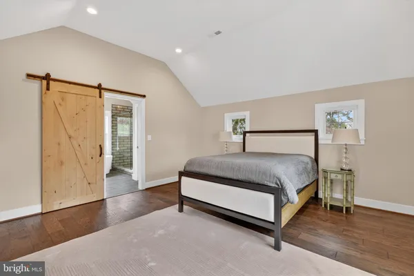a spacious bedroom with a bed and wooden floor