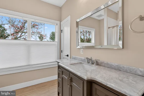 a bathroom with a granite countertop sink a mirror and a shower