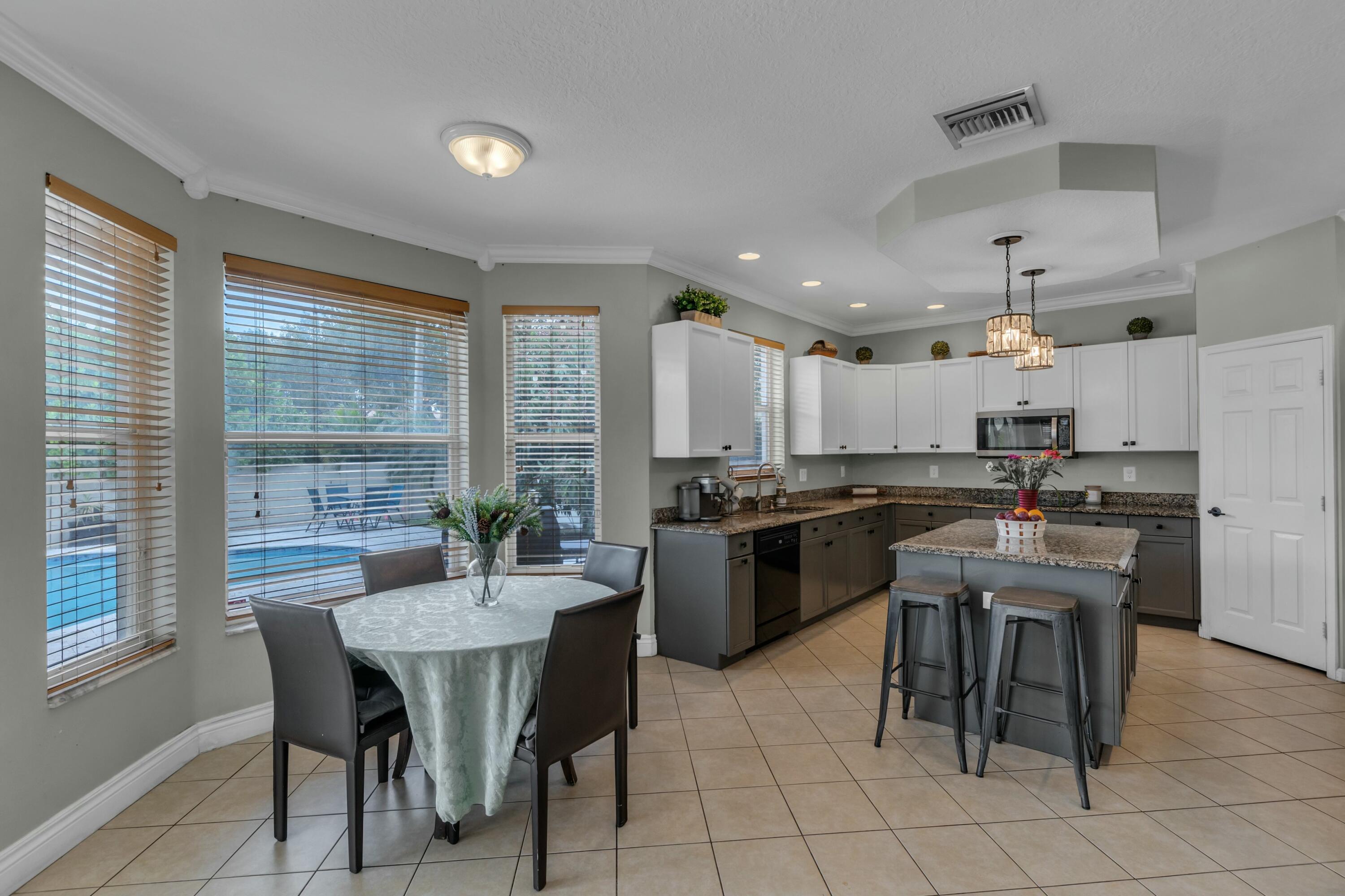 9895 Shepard Place Wellington, FL 33414 - Photo 15 of 60 a kitchen with a dining table chairs and refrigerator