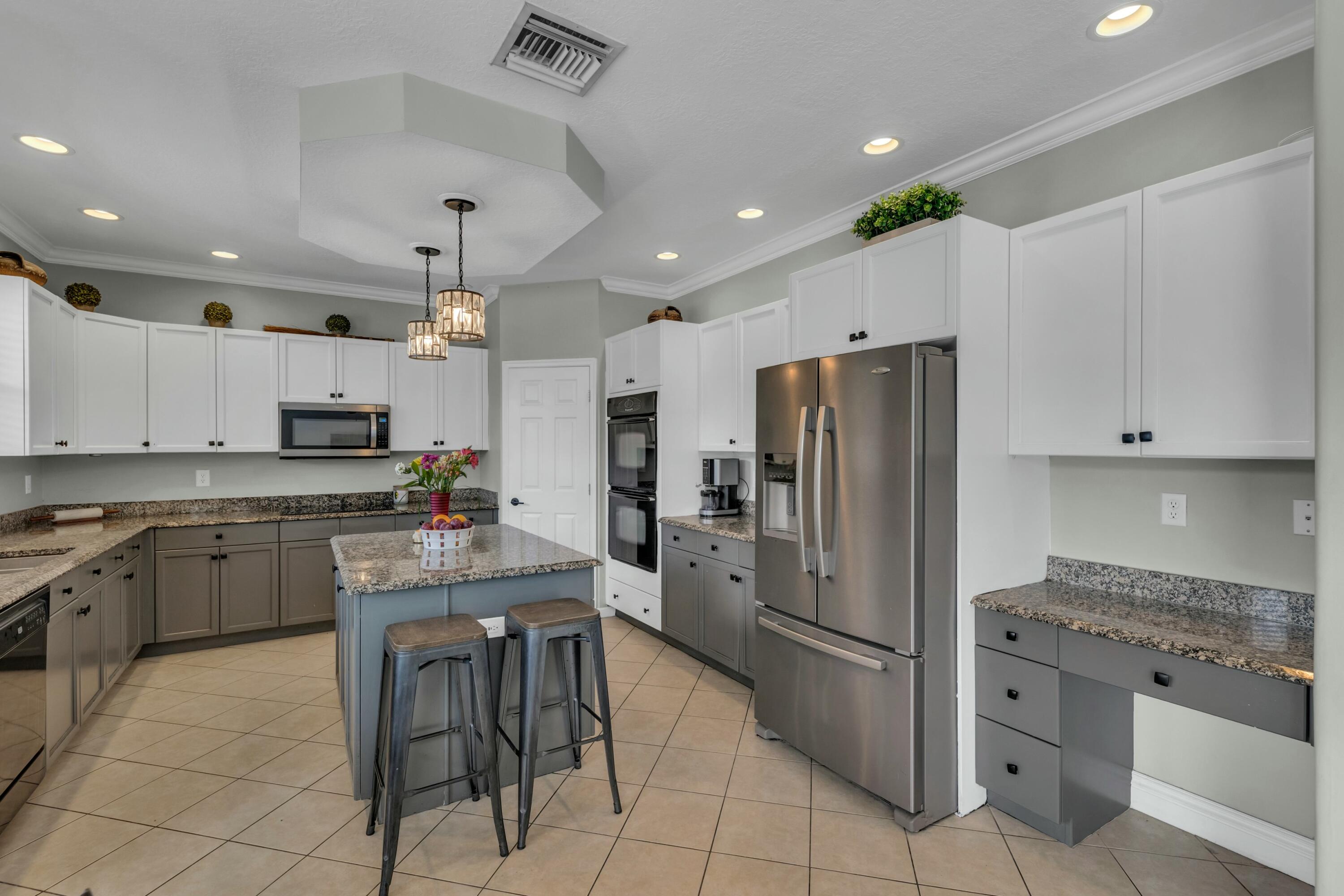 9895 Shepard Place Wellington, FL 33414 - Photo 16 of 60 a kitchen with stainless steel appliances granite countertop a refrigerator a sink a stove a microwave and island