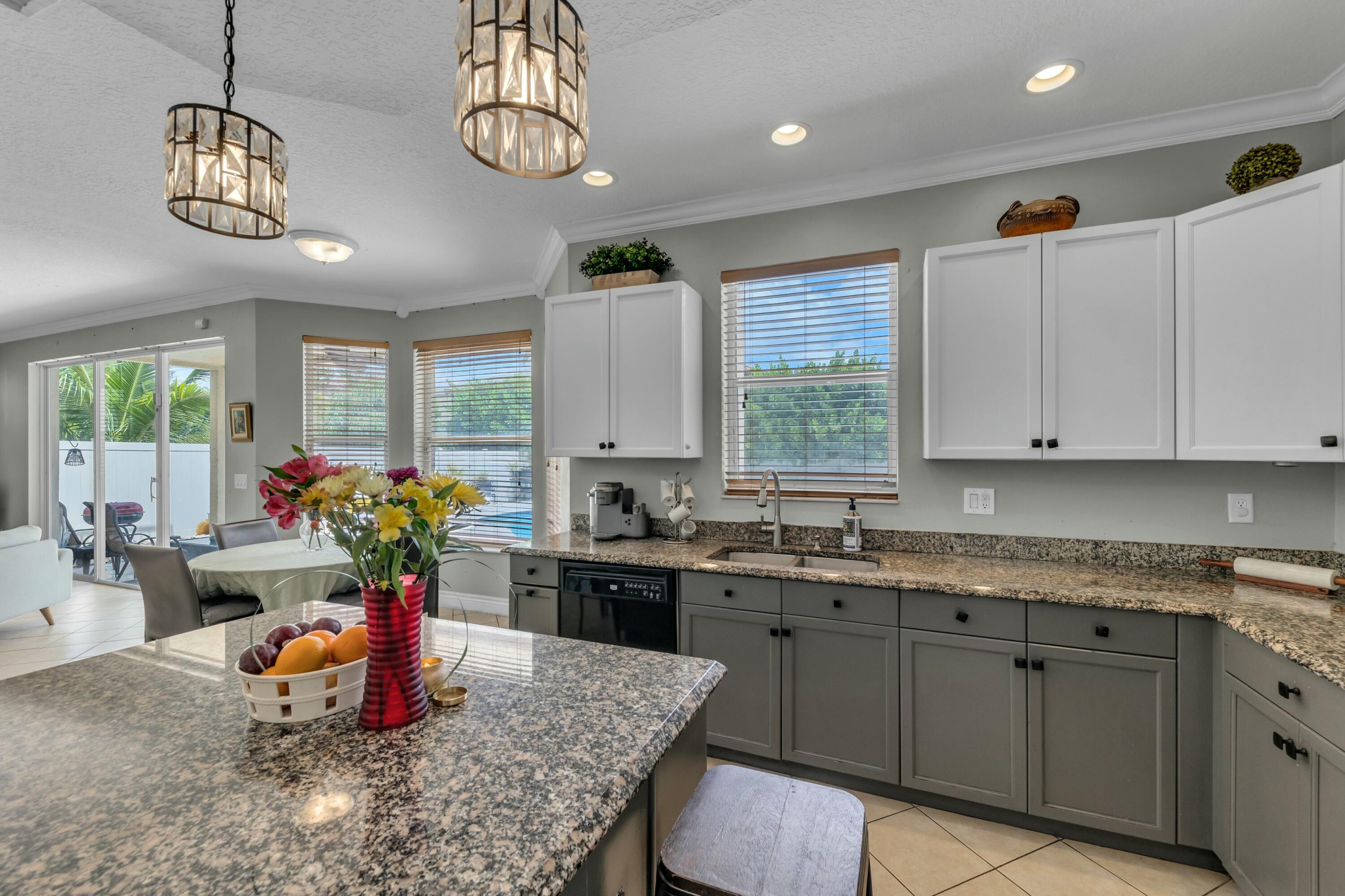 9895 Shepard Place Wellington, FL 33414 - Photo 19 of 60 a kitchen with stainless steel appliances granite countertop a sink dishwasher a stove a dining table and chairs with wooden floor