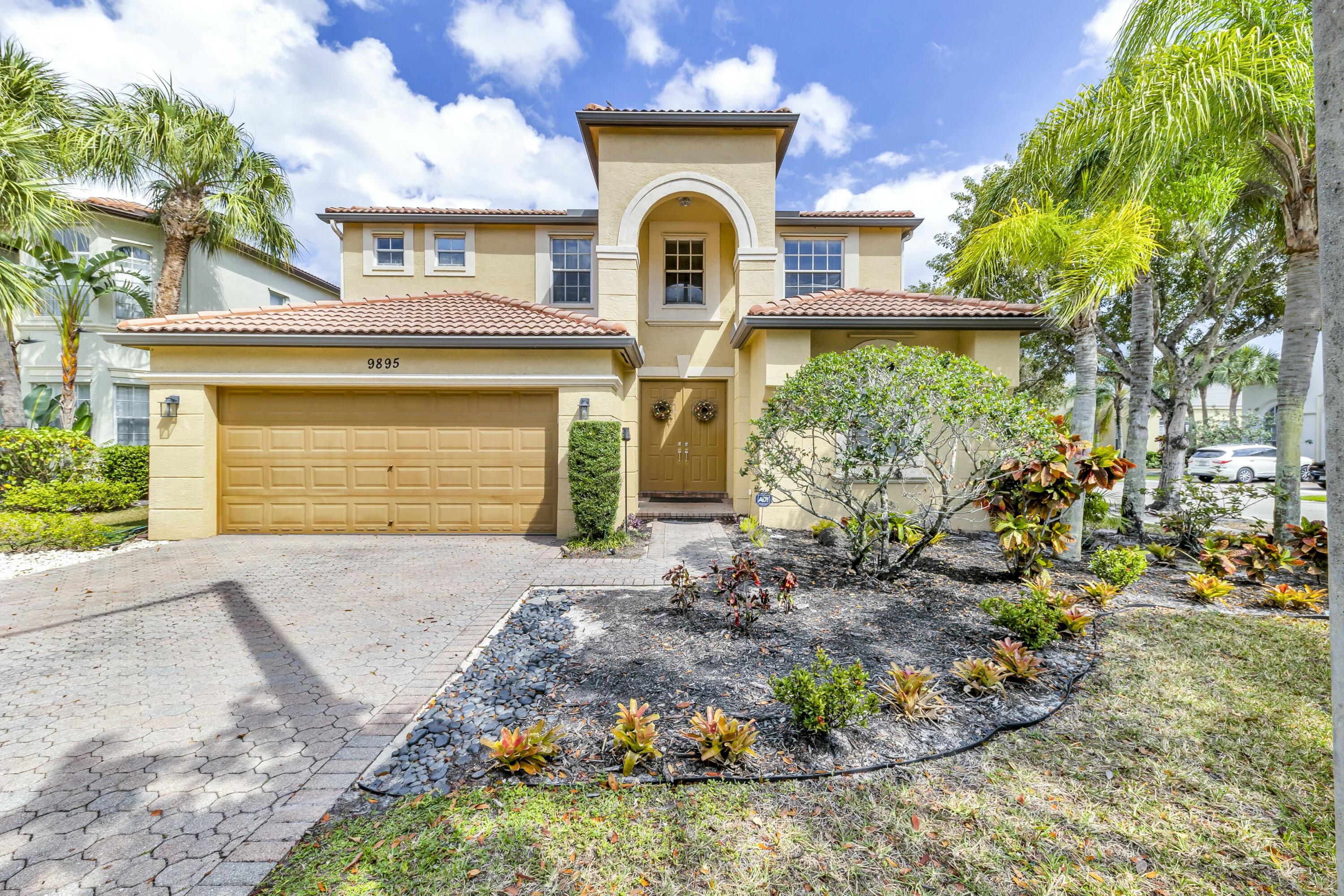 9895 Shepard Place Wellington, FL 33414 - Photo 2 of 60 a front view of a house with a garden