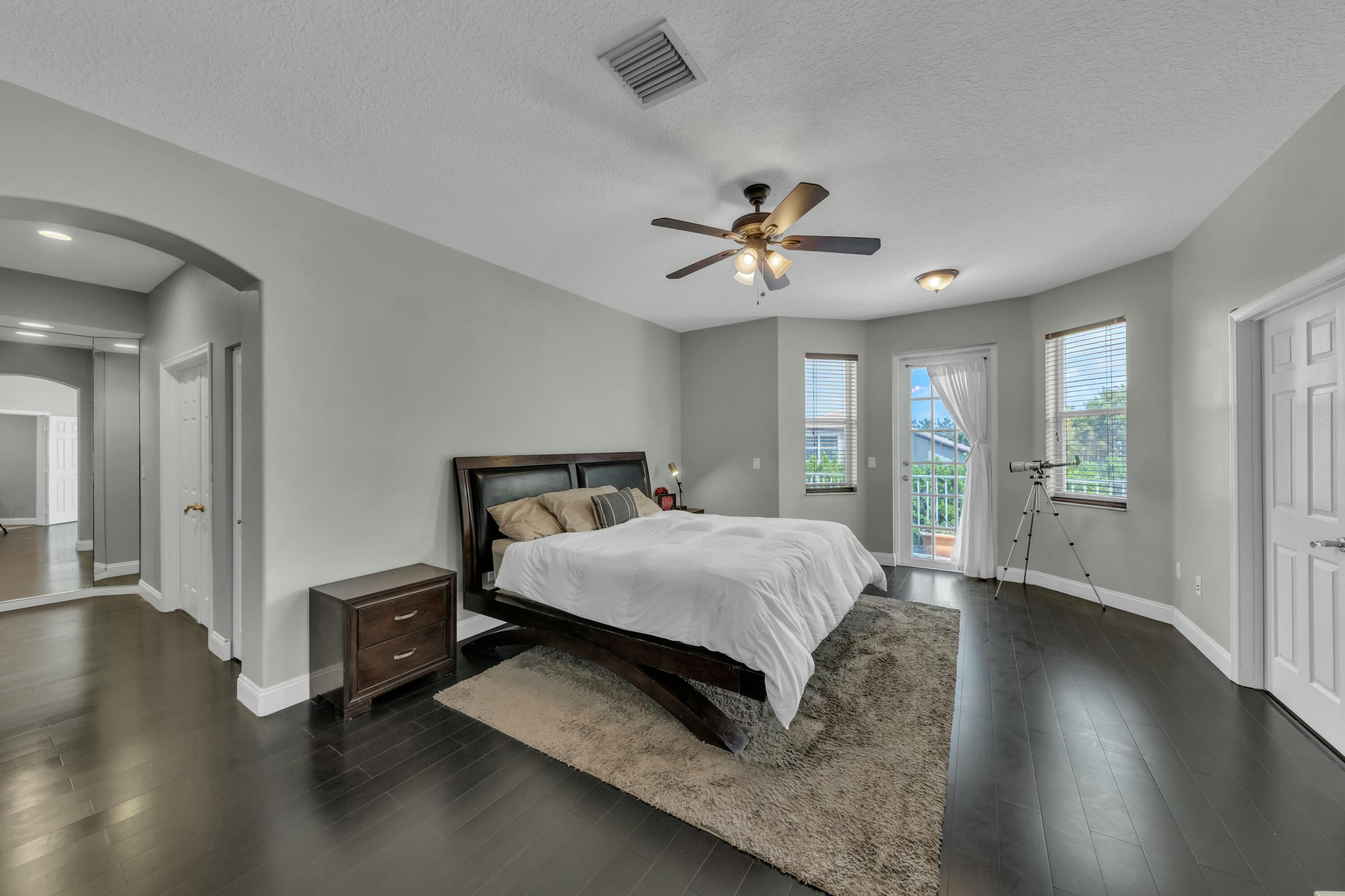 9895 Shepard Place Wellington, FL 33414 - Photo 33 of 60 a spacious bedroom with a bed a window and wooden floor
