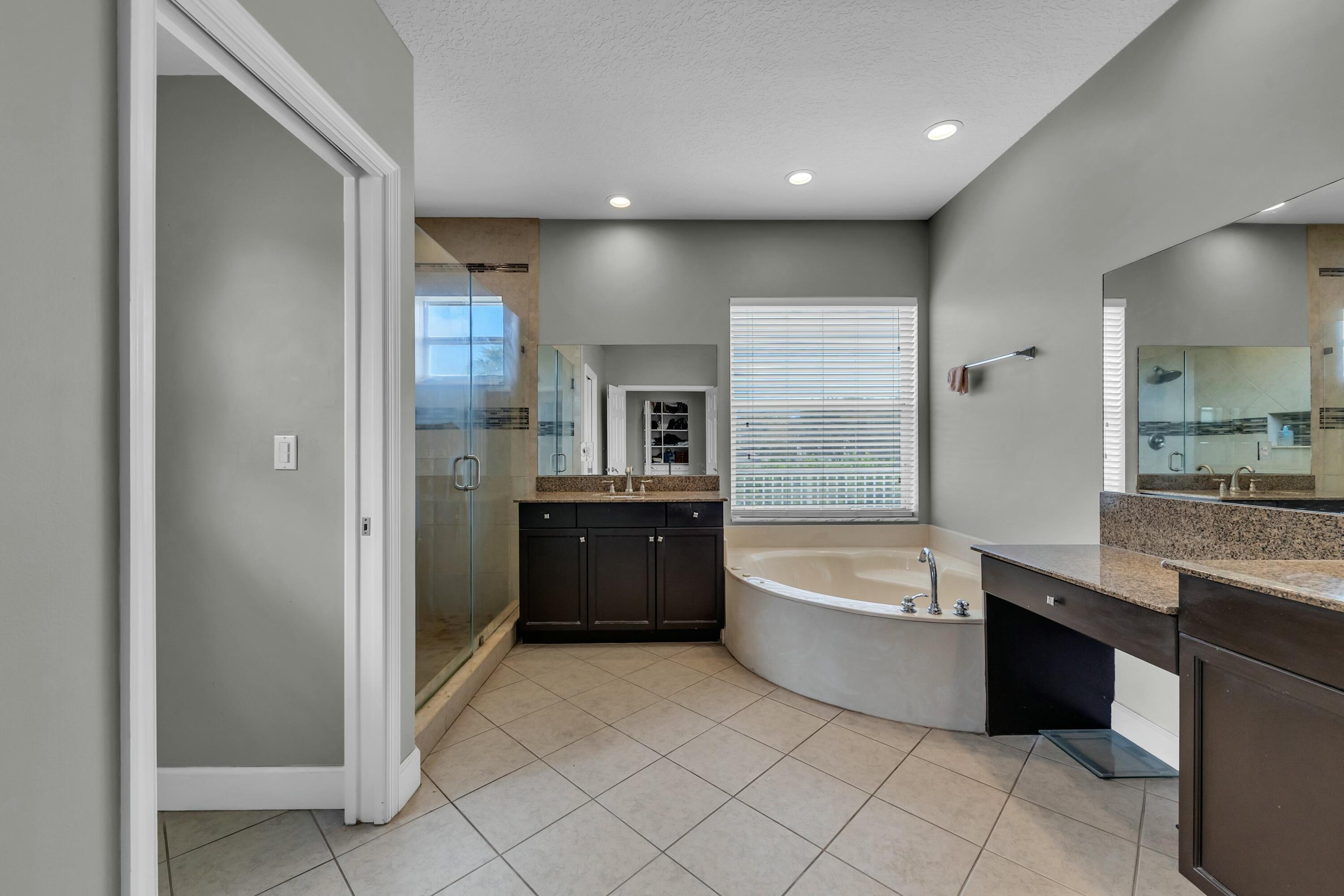 9895 Shepard Place Wellington, FL 33414 - Photo 38 of 60 a bathroom with a bathtub a sink a mirror and a shower