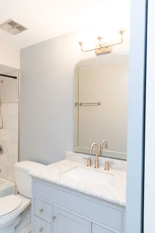 a bathroom with a granite countertop sink a toilet and mirror