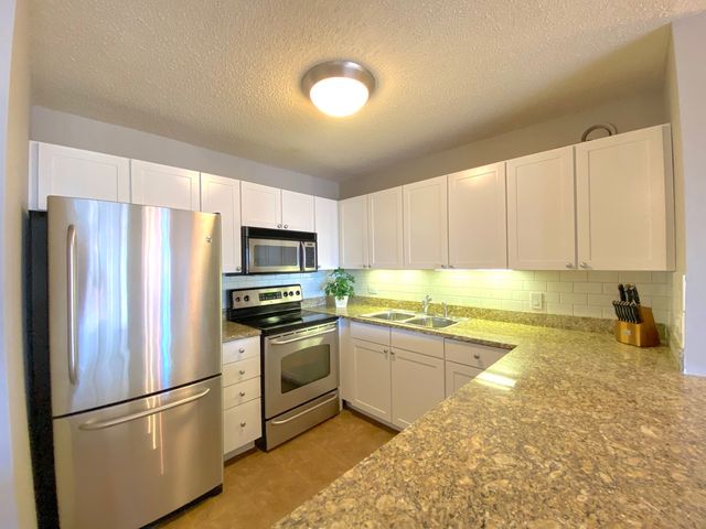 a kitchen with granite countertop a sink stove and cabinets