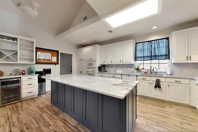 a kitchen with stainless steel appliances granite countertop a stove top oven a sink dishwasher and white cabinets with wooden floor