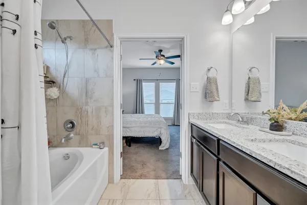 a bathroom with a granite countertop tub sink and mirror