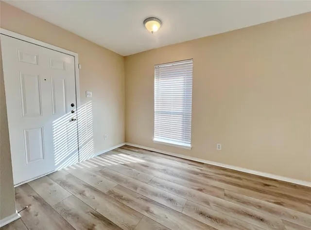 a view of an empty room with wooden floor and a window