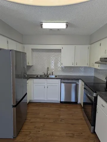 a kitchen with granite countertop a refrigerator stove top oven and sink