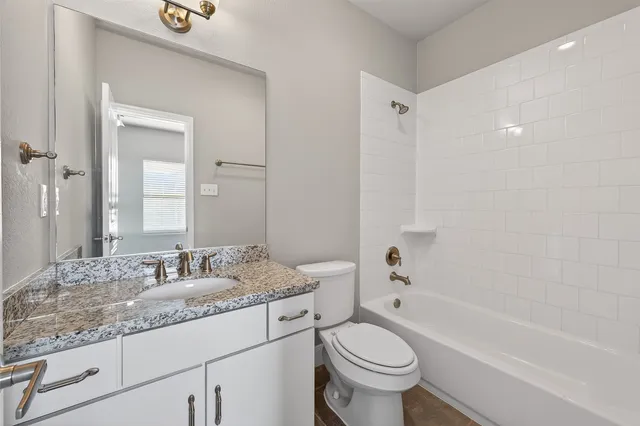 a bathroom with a granite countertop toilet a sink and a bathtub