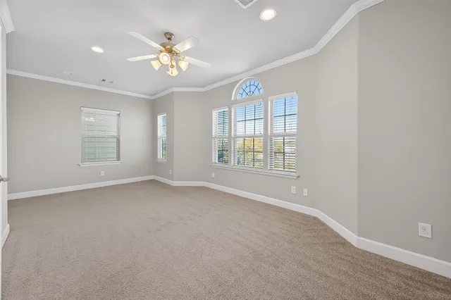 an empty room with windows and ceiling fan