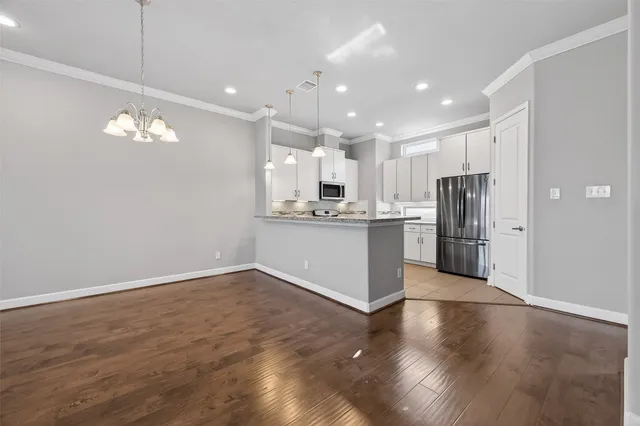 a view of kitchen with kitchen island stainless steel appliances cabinets and wooden floor