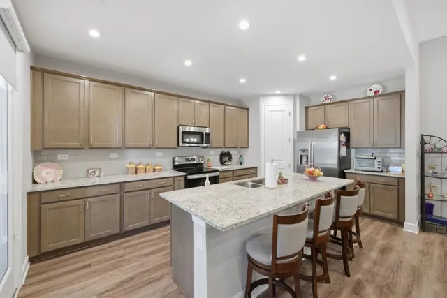 a kitchen with stainless steel appliances a dining table chairs refrigerator and microwave