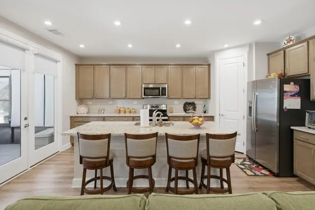a kitchen with refrigerator a stove and chairs