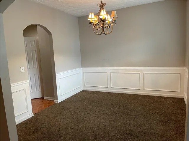 an empty room with wooden floor and chandelier