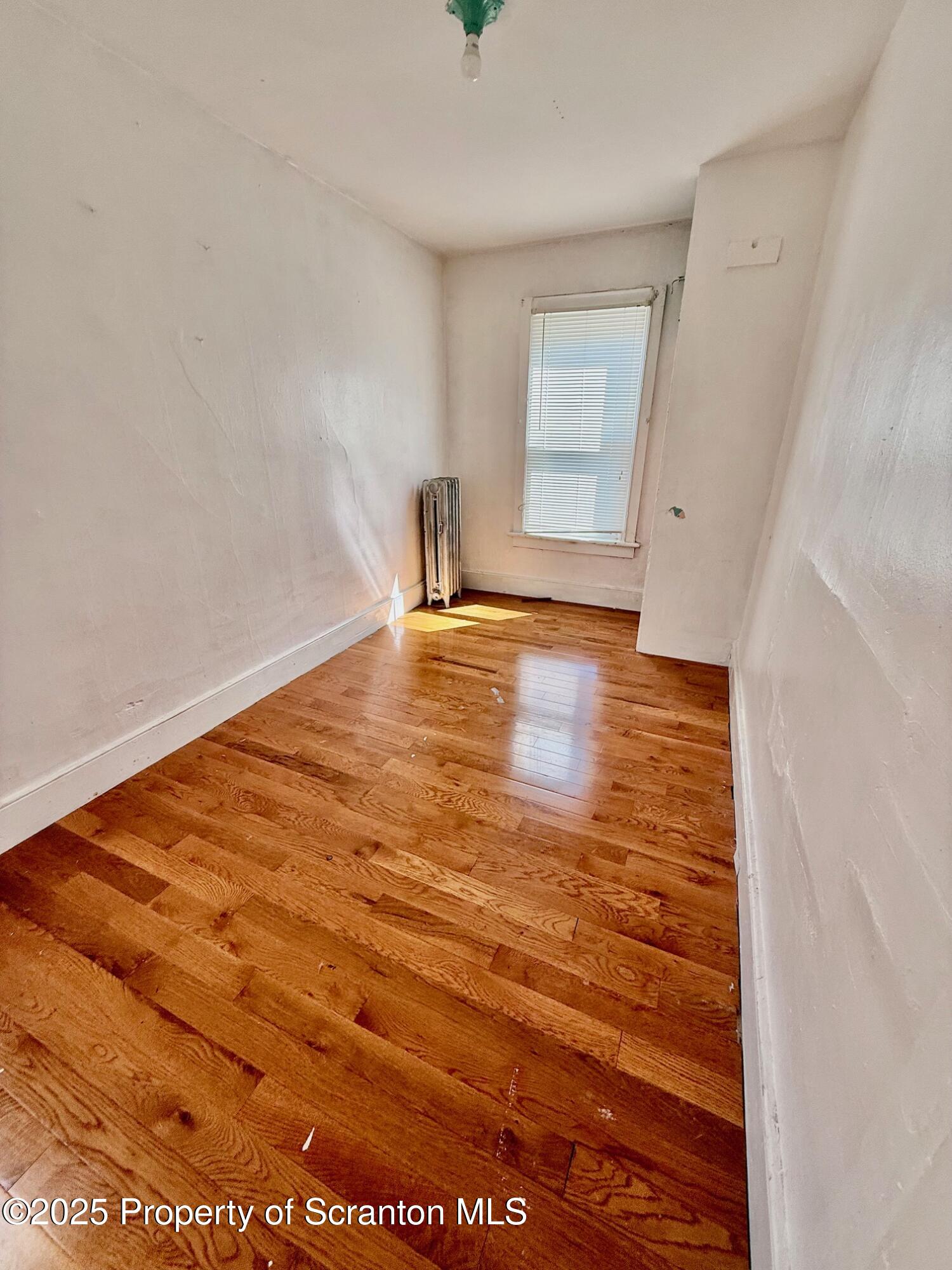 97 Washington Street Carbondale, PA 18407 - Photo 12 of 18 a view of an empty room with wooden floor and a window