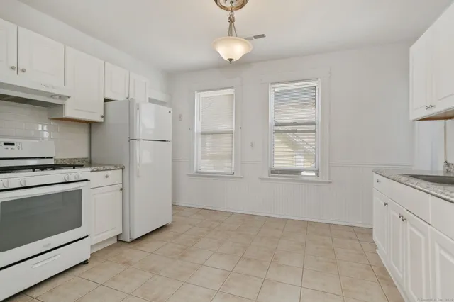 a kitchen with white cabinets and white appliances