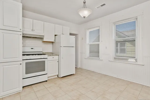 a kitchen with white cabinets and white appliances